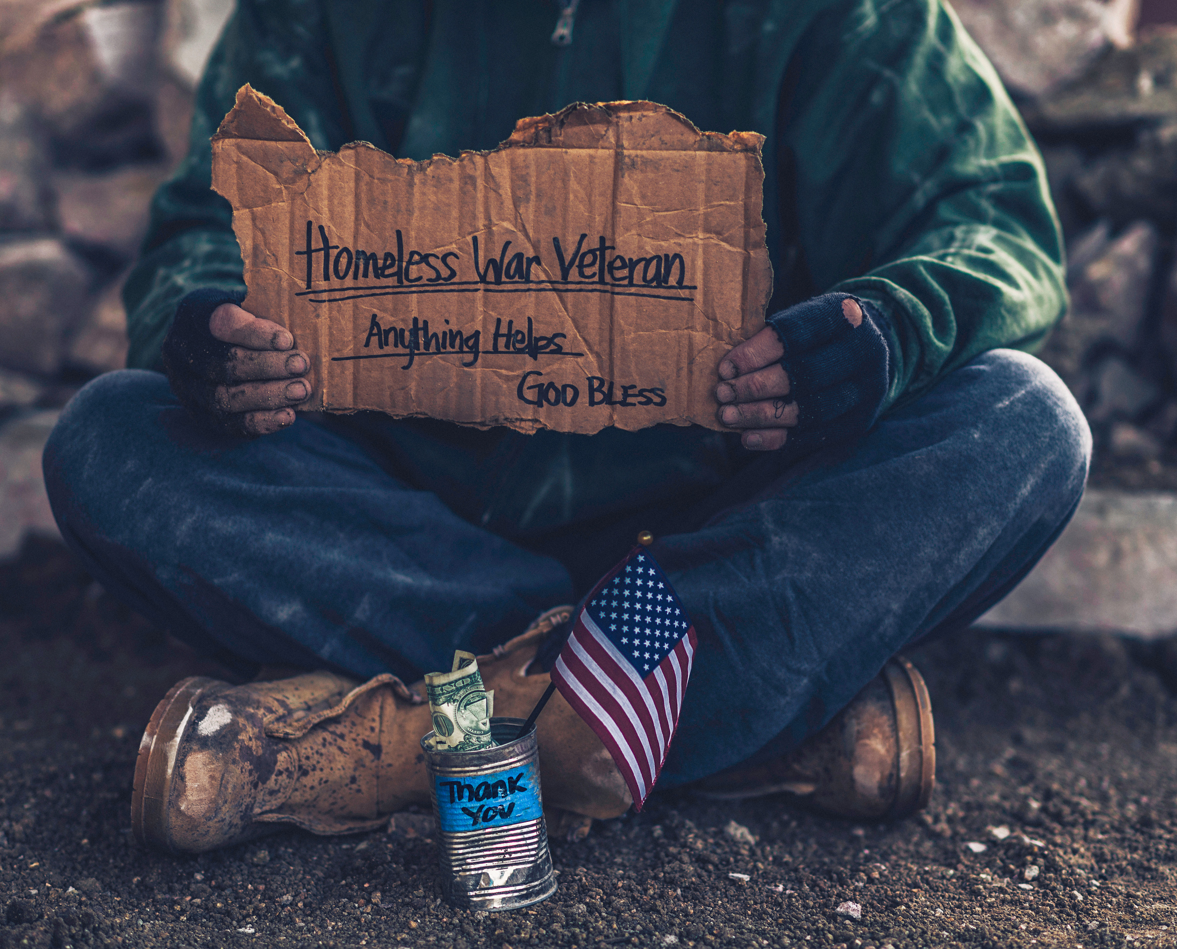 Fighting adversity. Homeless war veteran with sign and money tin
